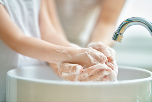 Parent and kids washing hands in sink with foamy soap