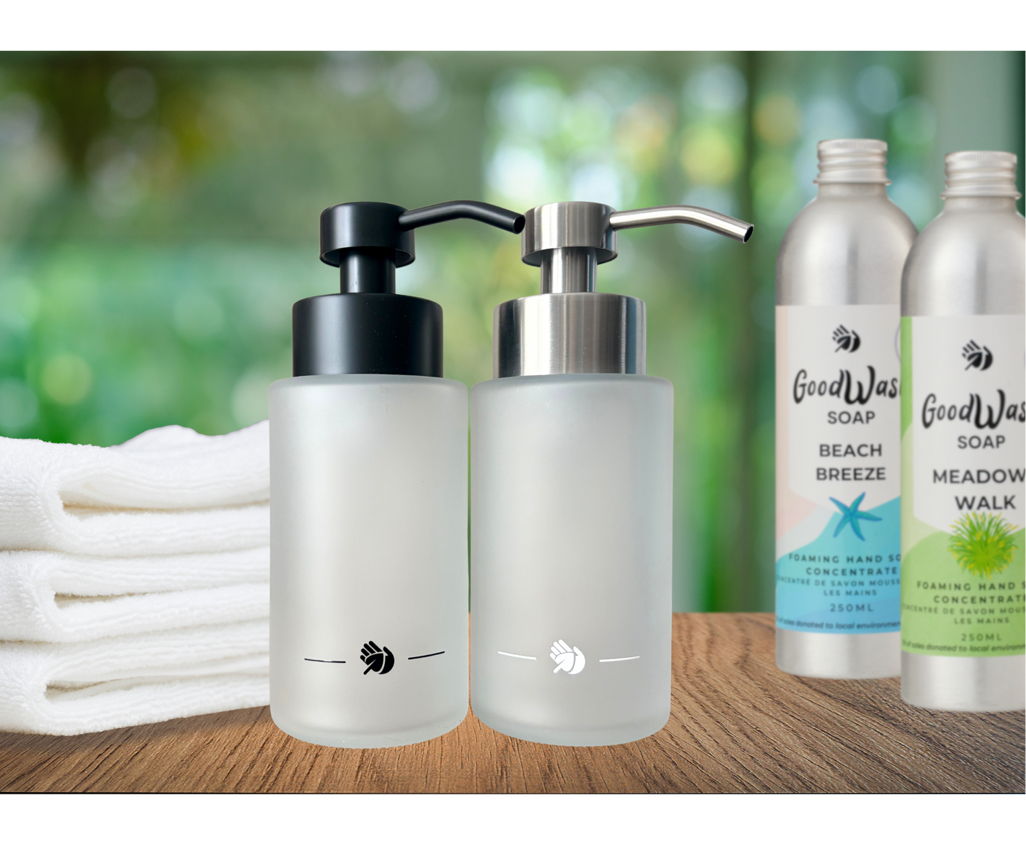Two soap dispensers and a stack of white towels on a wooden surface with a blurred green background.